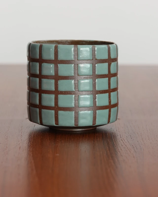 Cup with a blue-green glazed grid over brown clay