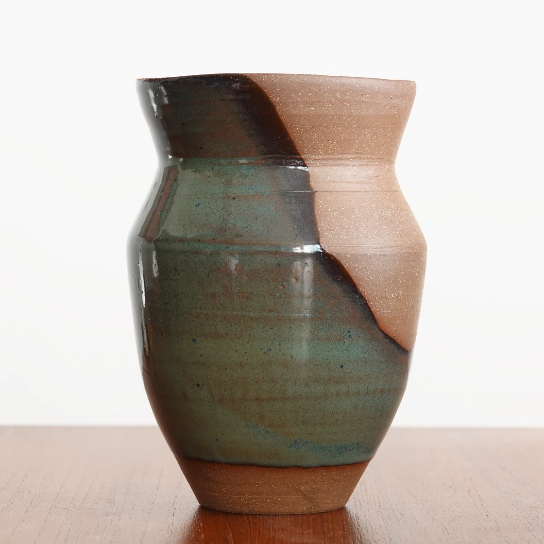 Glazed vase with flowing green glaze and exposed brown clay