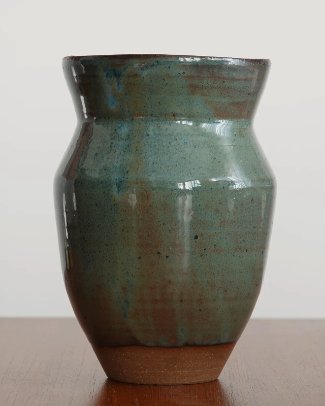 Wheel-thrown vase with flowing blue-green glaze and exposed clay